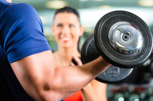 Entrenador personal en gimnasio y entrenamiento con mancuernas