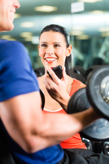 Foto entrenador personal en gimnasio y entrenamiento con mancuernas