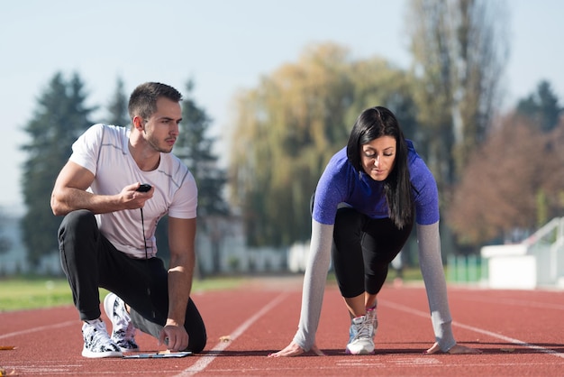 Entrenador personal guapo que ayuda a la mujer a correr en la pista de atletismo en el área del parque de la ciudad entrenando y haciendo ejercicio para el concepto de estilo de vida saludable de resistencia al aire libre