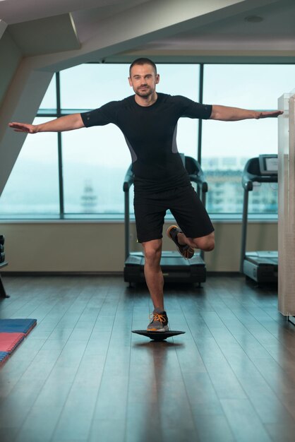 Entrenador personal haciendo un ejercicio con Bosu Balance Ball como parte del entrenamiento de culturismo