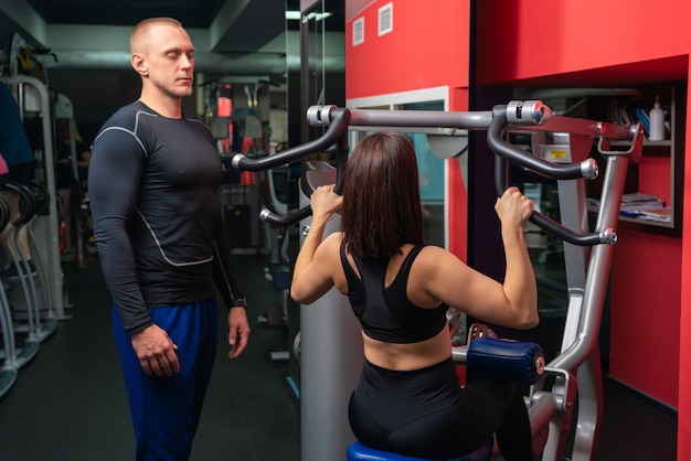 Entrenador personal hombre trabajando con una mujer joven en el gimnasio moderno