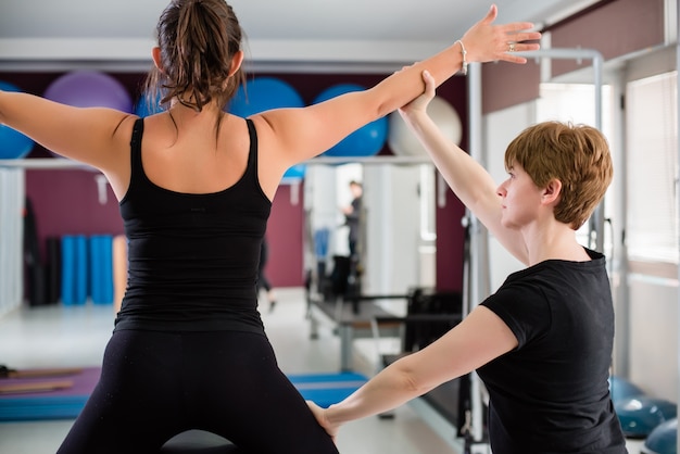 Entrenador personal que supervisa a la mujer que se extiende en un barril de escalera de pilates