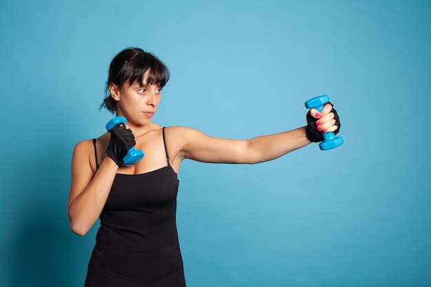 Entrenador personal sosteniendo pesas estirando los músculos del brazo durante el entrenamiento físico en el estudio. Persona en forma atlética que trabaja en un estilo de vida saludable practicando actividad deportiva. concepto de gimnasio