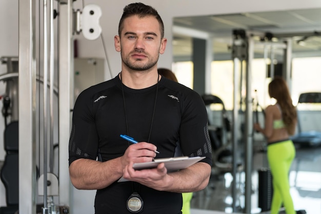 Foto entrenador personal toma notas mientras la mujer hace ejercicio de bíceps