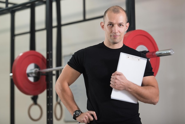 Entrenador personal toma notas en el portapapeles en el gimnasio del gimnasio