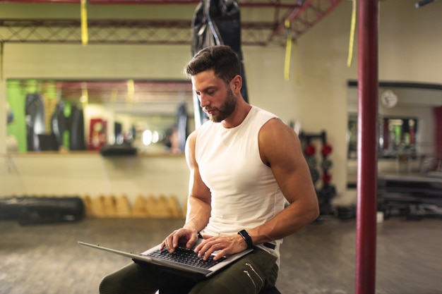 Foto entrenador personal usando una laptop en el gimnasio.