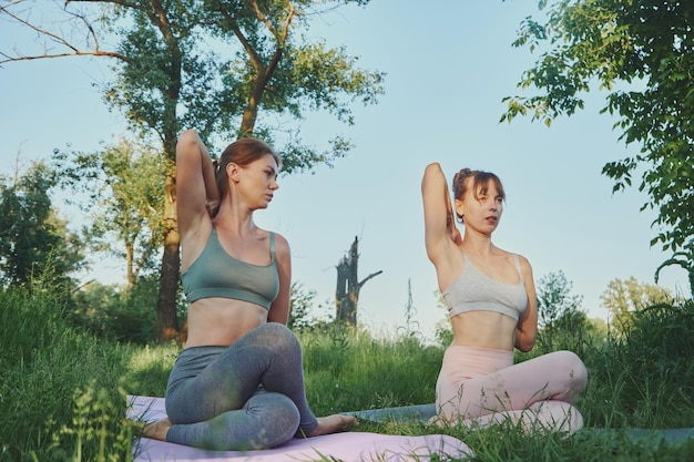 Entrenador personal de yoga enseñando a una mujer joven o a su amiga gomukhasana al aire libre