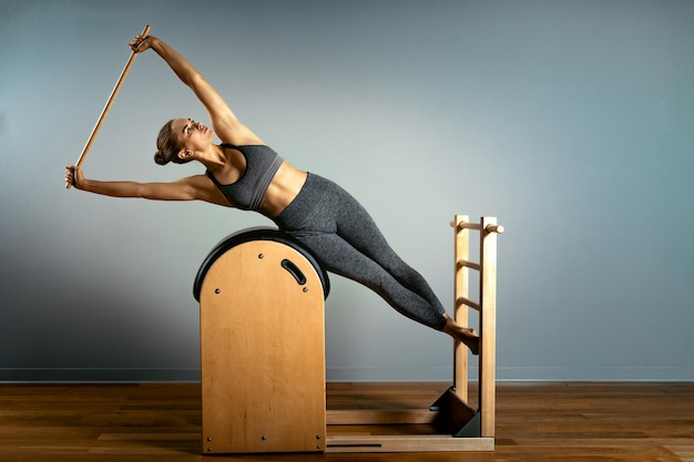 Foto entrenador de pilates ejercicios en un barril de pilates entrenamiento del cuerpo forma y postura corporal perfecta