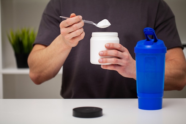 Entrenador prepara un batido de proteínas en el agitador después del entrenamiento