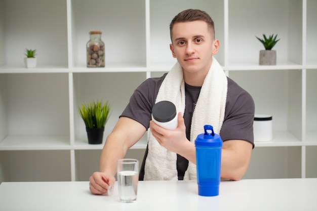 Entrenador prepara un batido de proteínas en el agitador después del entrenamiento