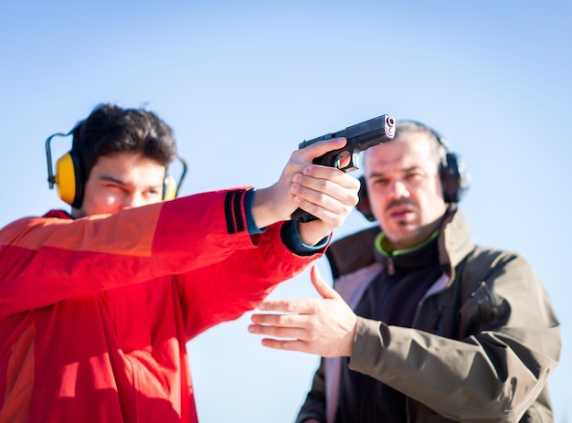 Entrenador que ayuda a los jóvenes a apuntar con una pistola en el entrenamiento de combate. foto de alta calidad