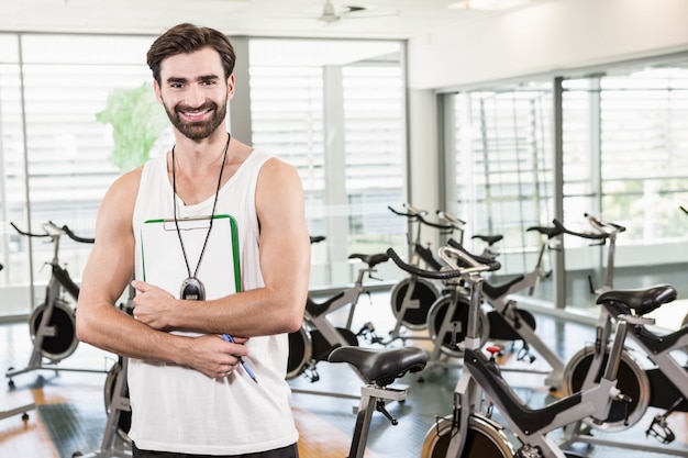 Entrenador sonriente mirando a la cámara en el gimnasio