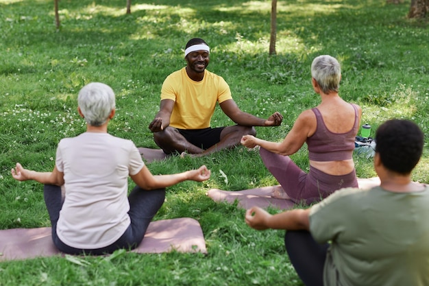 Foto entrenador de yoga masculino con un grupo de mujeres mayores disfrutando de la meditación al aire libre