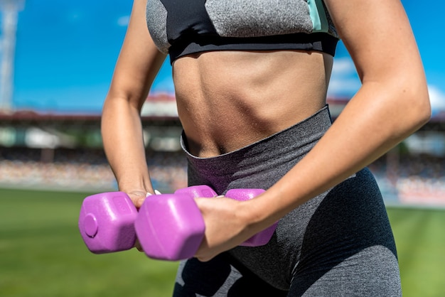 Entrenadora atlética en ropa deportiva haciendo ejercicio con pesas en el estadio sity. Estilo de vida activo