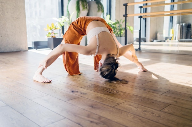 La entrenadora de yoga femenina hace ejercicio en el gimnasio de aeróbicos corporales flexibles