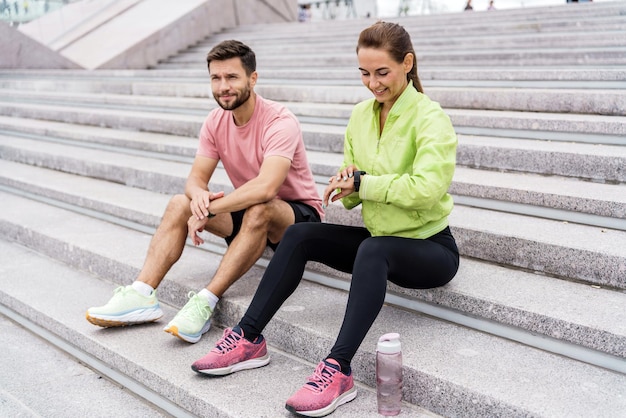 Los entrenadores de entrenamiento de personas usan un reloj de fitness y una aplicación para obtener resultados de ejercicio. Una mujer y un hombre en fitness.