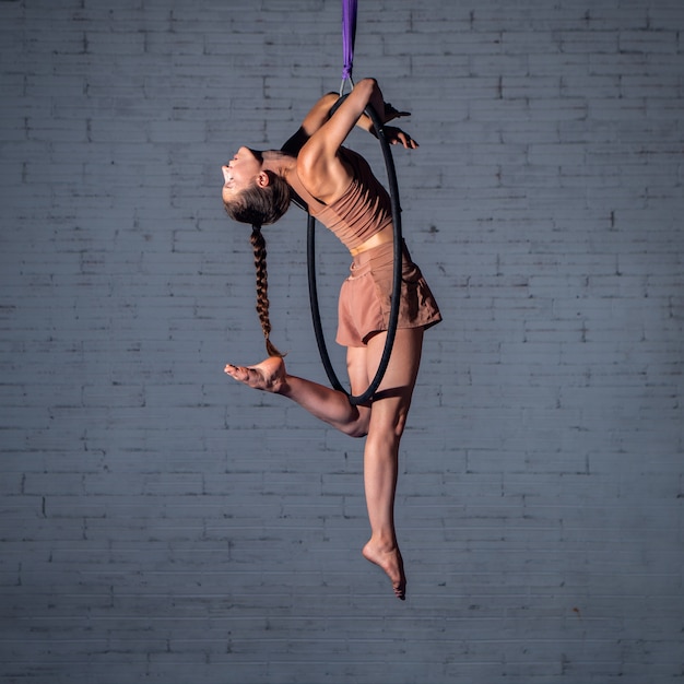 Entrenamiento de acróbata trapecista de circo femenino en el aro