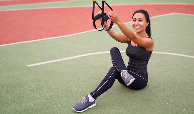 Entrenamiento de atleta chica usando trx en sportground