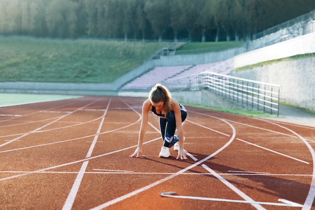 Entrenamiento de la atleta femenina en la pista de atletismo en la luz de la mañana joven corredor