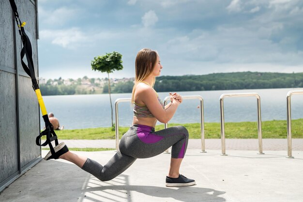 Entrenamiento de atleta femenino delgado joven con trx en la naturaleza. Estilo de vida saludable. Haz que tu cuerpo sea una máquina