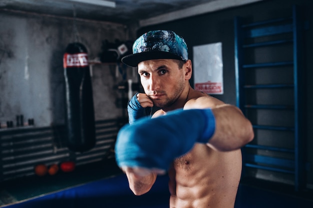 Entrenamiento de boxeador en el gimnasio oscuro. Kick-box muscular o luchador de muay thai