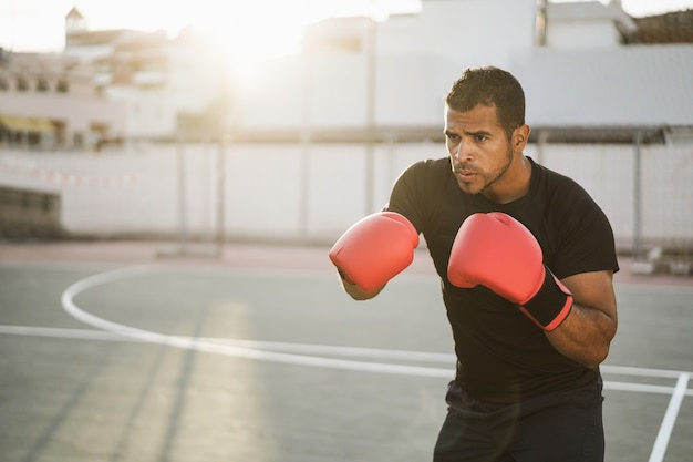 Entrenamiento de boxeador profesional al aire libre en el parque de la ciudad - Enfoque suave en el guante izquierdo