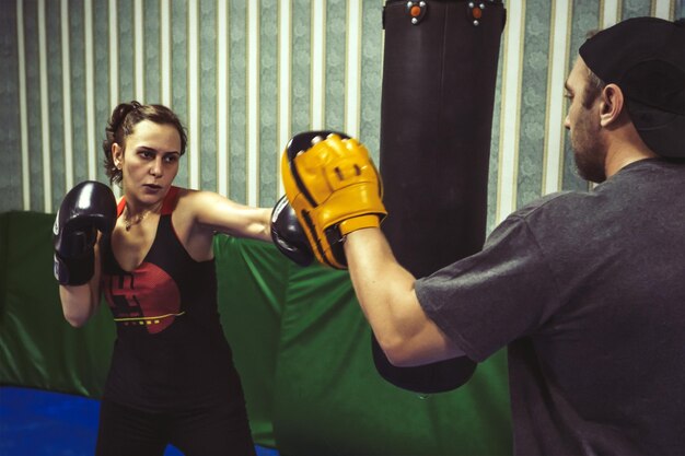 Foto entrenamiento de boxeadoras con instructor de fitness masculino en el gimnasio