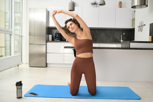 Entrenamiento en casa mujer joven entrenamiento en casa estirando su cuerpo haciendo ejercicios de fitness en goma de yoga