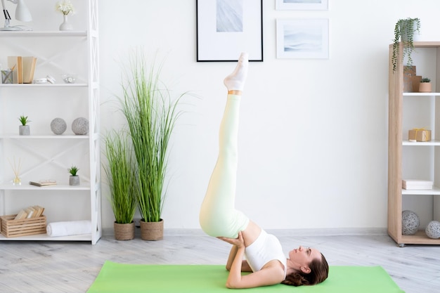 Entrenamiento corporal Salud deportiva Fuerza muscular Mujer fuerte en ropa deportiva haciendo ejercicio de gimnasia en colchoneta de yoga en el interior del gimnasio en casa