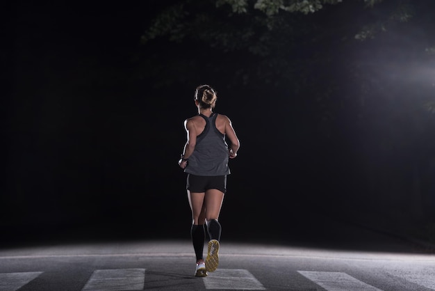 Entrenamiento de corredora muscular en forma para correr maratón por la noche en un hermoso camino en la naturaleza.