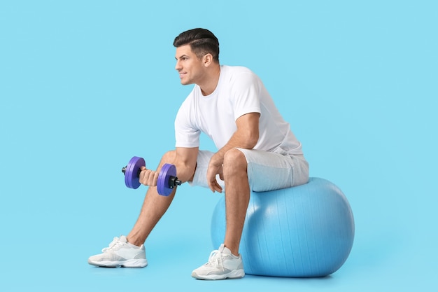 Entrenamiento deportivo joven con mancuernas en la superficie de color