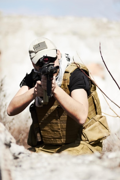 Entrenamiento de destino Un soldado se agachó y apuntó su arma a la cámara durante un entrenamiento en un entorno desértico