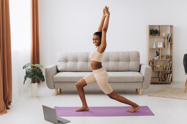 Entrenamiento doméstico joven mujer negra deportiva haciendo ejercicio de tablón en casa entrenando en la sala de estar