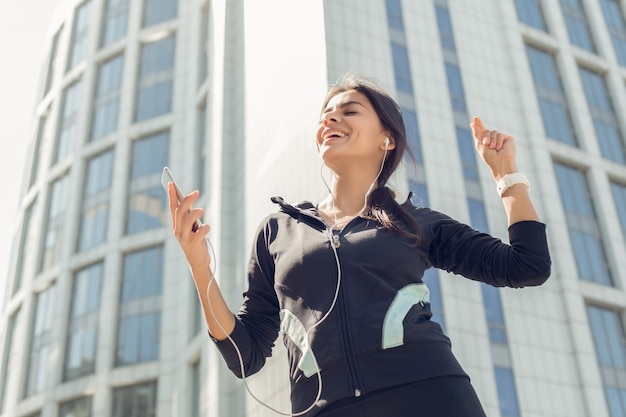 Foto entrenamiento de ejercicio activo femenino joven en la calle fuera de escuchar música