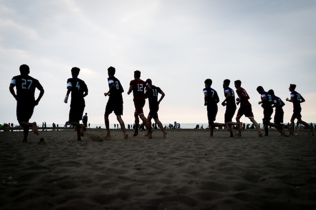 Entrenamiento en equipo de niños pequeños en la playa al atardecer