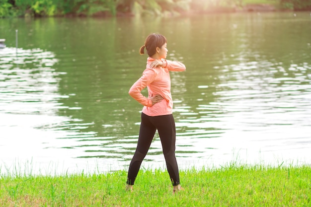 Entrenamiento femenino joven antes de la sesión de entrenamiento de la aptitud en el parque. Mujer joven sana que calienta al aire libre.