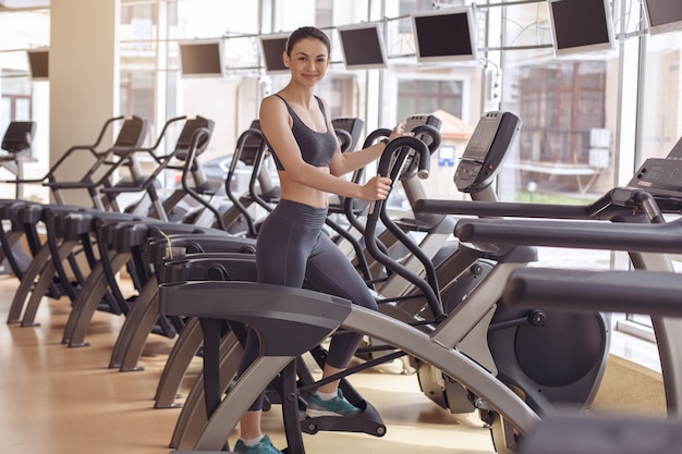 Entrenamiento femenino joven en el entrenador elíptico gimnasio estilo de vida saludable