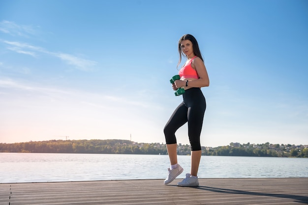 Entrenamiento físico - ejercicio de trabajo de hermosa mujer joven con pesas, como parte de su estilo de vida.