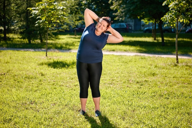 Foto entrenamiento físico de fat femme en la naturaleza acrobacias en tierra o estiramiento en parterre