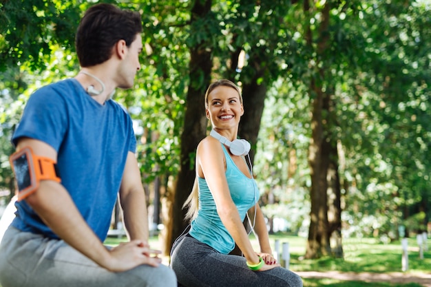 Entrenamiento de flexibilidad. Alegre mujer deportiva sonriendo a su novio mientras realiza entrenamiento de flexibilidad