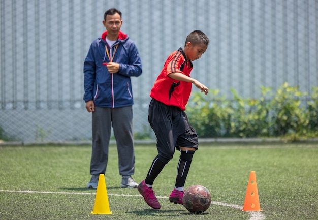 Entrenamiento de fútbol soccer para niños. Entrenador explicando el plan de juego. Los muchachos mejoran las habilidades futbolísticas locales de Tailandia