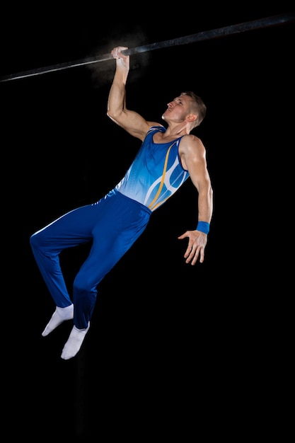 Entrenamiento de gimnasta masculino muscular en gimnasio, flexible y activo. Caucásico ajuste chico ropa deportiva azul