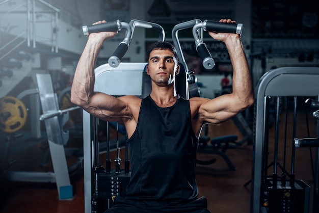 Entrenamiento de hombre bronceado en máquina de ejercicio