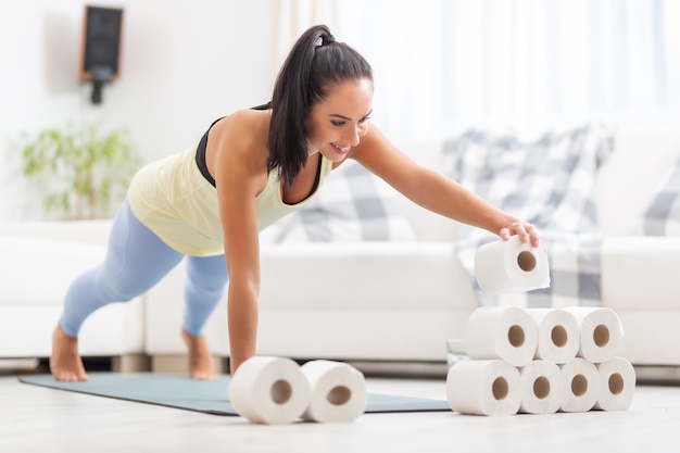 Entrenamiento inspirado en Covid por una mujer en forma que apila rollos de papel higiénico en posición de tabla.