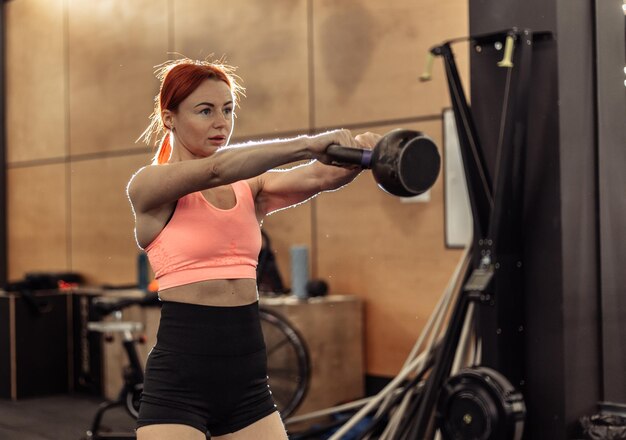 Entrenamiento intensivo de una mujer pelirroja con un timbre en la mano en un gimnasio moderno