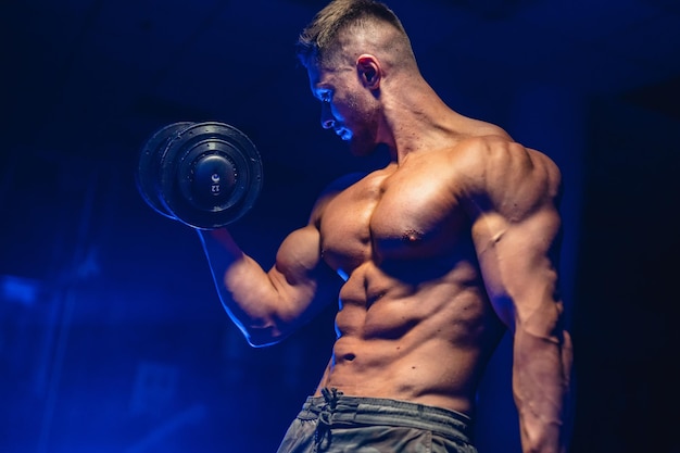 Entrenamiento masculino de culturismo guapo Hombre atlético fuerte sobre fondo azul