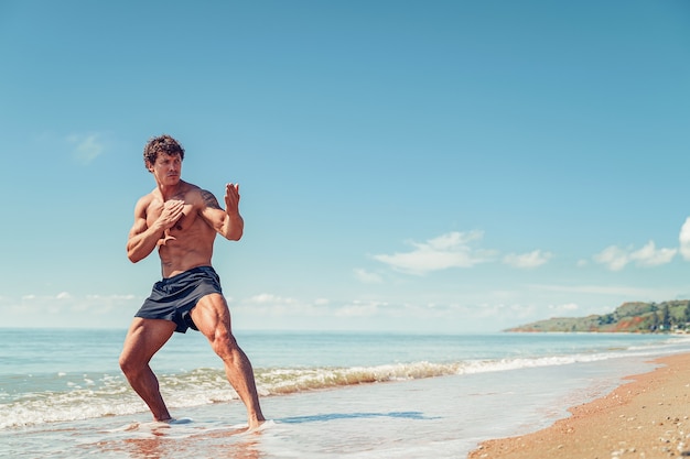 Un entrenamiento de muay thai o kickboxer con boxeo de sombra al aire libre en la orilla del mar