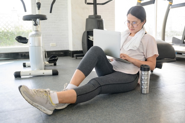 Entrenamiento de mujer asiática y trabajando solo en línea en GYM. Distanciamiento social y nuevo estilo de vida normal.