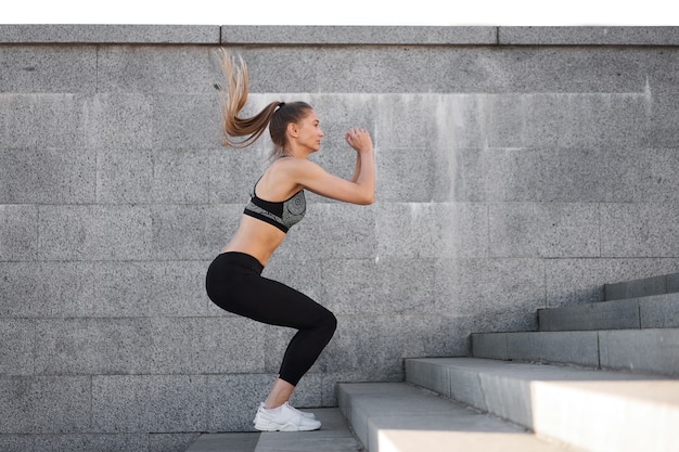 Entrenamiento de mujer deportiva urbana. Atleta femenina haciendo sentadillas en escaleras urbanas