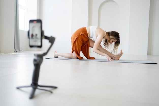 Entrenamiento de mujer de yoga por teléfono en línea en un elegante gimnasio